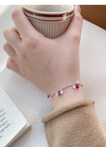 Détail du bracelet en argent S925 avec zircon rose au poignet tenant une tasse