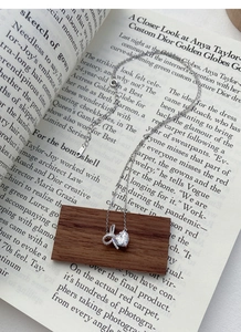Detailed close-up of S925 silver heart necklace with bow pendant on an open book