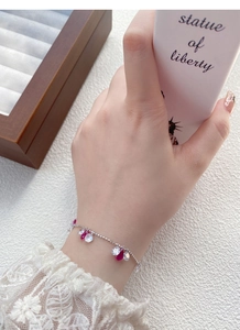 Détail d'un bracelet en argent S925 avec zircons en forme de goutte rose rouge sur le poignet