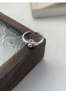 Close-up of S925 sterling silver bow ring with bead detail on a dark wooden box