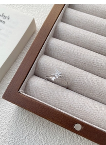 Detailed shot of S925 sterling silver butterfly ring with sparkling zircon on wooden tray