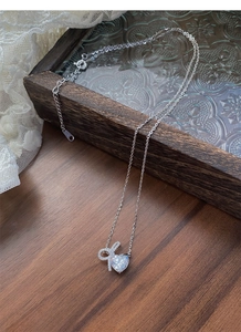 Close-up of S925 sterling silver bow heart necklace with sparkling zircon on a wood tray