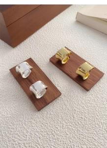 Dettaglio di orecchini larghi curvi irregolari con finitura oro e argento lucido