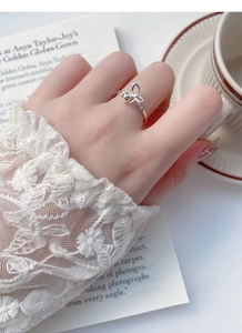 Detailed close-up of a silver bow ring with small bead on hand in a French lifestyle setting