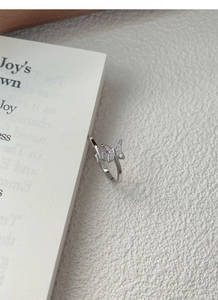 Close-up of S925 sterling silver butterfly ring with cubic zirconia on textured background