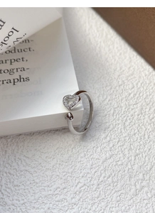 Macro detail of silver S925 heart ring with cubic zirconia stones on a book