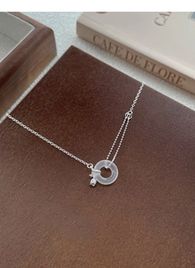 Détail du collier tulipe en argent S925 avec anneau en jade sur un fond en bois