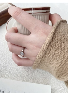 Detail of S925 sterling silver snowflake ring worn while holding a ceramic cup