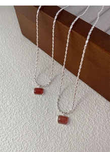Detail of S925 sterling silver chain with rectangular strawberry crystal pendant on wood