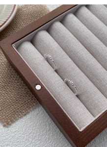 Close-up of S925 sterling silver bow rings displayed on a wooden jewelry tray