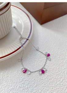 Détail du bracelet perlé en argent S925 avec zircons rouges en forme de poire sur table