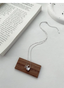 Detail of S925 silver necklace featuring a heart-shaped zircon and diamond bow pendant