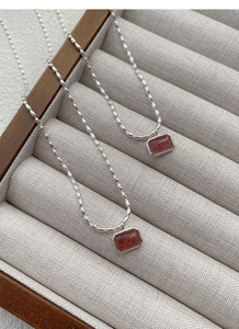 Macro detail of S925 silver necklace with rectangular strawberry quartz gemstone pendant