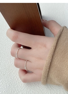 Detail of stacked S925 sterling silver bow rings on fingers with elegant hollow design
