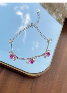 Détail macro d'un bracelet en argent S925 avec cristaux gouttes roses sur surface miroir