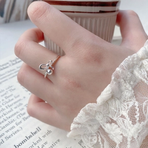 S925 sterling silver bow ring with round bead charm shown on a hand holding a cup