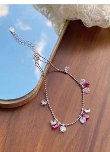 Détail du bracelet en argent S925 avec zircons rouges en goutte sur table en bois