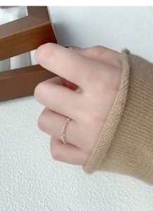 Detailed view of silver bow-knot rings on fingers with a cozy knit sweater background