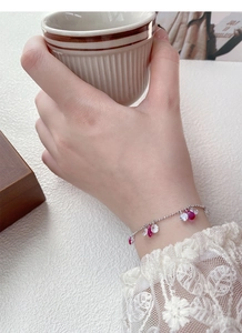 Détail du bracelet en argent S925 avec zircons rouges en goutte sur poignet féminin