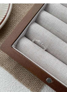 Detail of S925 sterling silver bow ring with twisted band on linen jewelry box