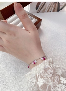 Gros plan d'un bracelet en argent S925 avec breloques goutte rouge rubis et zircons
