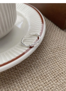 Macro detail of S925 sterling silver bow ring featuring a textured band on ceramic plate