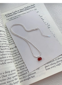 Detail of S925 silver beaded chain with rectangle red stone pendant and 925 authenticity tag