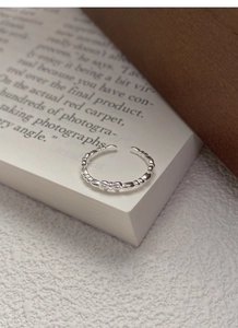 Close-up of S925 sterling silver bow ring on a book page with minimalist open design