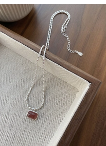 Detail of S925 silver necklace with rectangle strawberry quartz pendant on wooden tray