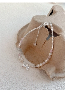 Macro shot of S925 silver bow pendant and pink pearl beads on an aesthetic stone background