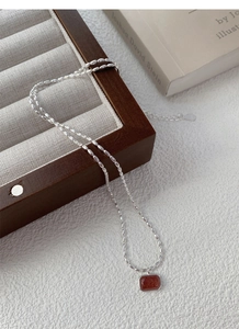 Macro shot of S925 silver beaded chain and rectangular goldstone pendant on a book