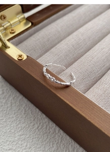 Detailed close-up of a silver bow knot open ring inside a wooden jewelry box