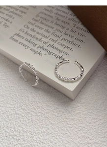 Close-up of a silver bow and beaded open ring set placed on an English book page