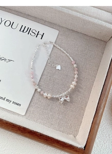 Detailed view of pink silver beads and natural freshwater pearl bracelet with bow charm