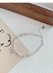 Detail of S925 silver bracelet with pink beads, freshwater pearls and a bow charm
