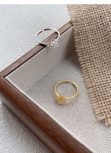 Detailed close-up of gold and silver S925 sterling silver bow rings on a wooden tray