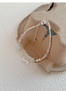 Detail of S925 silver bracelet with freshwater pearls and a delicate bow pendant