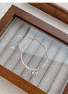 Detail of S925 silver beaded bracelet with pink gems, pearls and bow pendant in a box