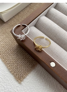 Detailed view of silver and gold knotted flower rings presented in a wooden jewelry box