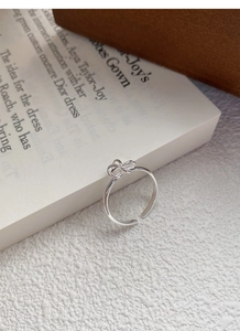 Detailed close-up of S925 sterling silver bow ring on an open book in soft lighting