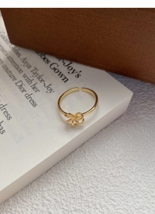 Detailed view of an elegant golden bow-shaped open ring placed on a vintage paper background