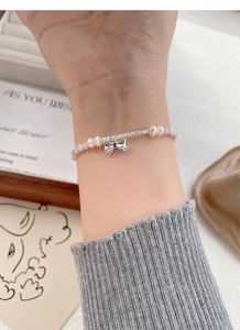 Detail of S925 silver bracelet with pink beads, freshwater pearls and a bow charm