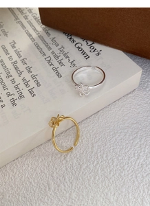 Detail of adjustable S925 silver bow rings in gold and silver finishes on a book