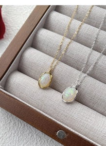 Detail of opal necklaces in gold and silver with wavy metal edges in a wooden jewelry box
