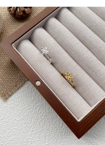 Detail of minimalist hollow flower rings in gold and silver finish on a wooden box