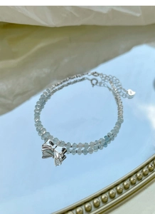 Detail of S925 sterling silver bow charm and aquamarine beads with mirror reflection