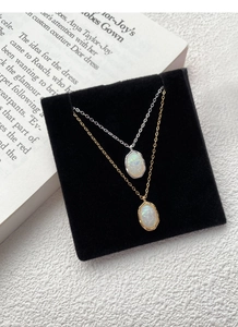 Detailed view of silver and gold opal necklaces displayed on elegant black velvet and magazine