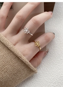 Close-up of gold and silver hollow flower rings worn on fingers in a lifestyle setting