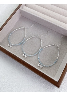 Detail of S925 sterling silver beaded bracelet with light blue gems and bow pendant