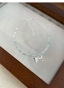 Detailed macro view of S925 silver beaded bracelet with blue aquamarine and bow charm
